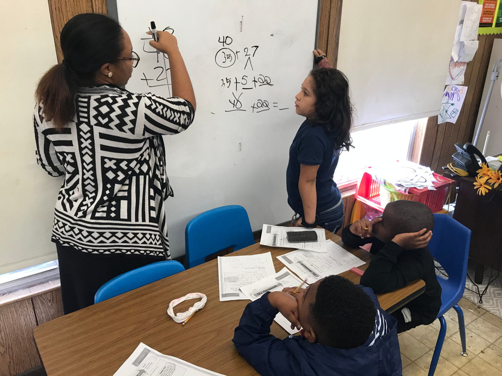 Kia Frazier-Williams teaching a small group of students math at the whiteboard